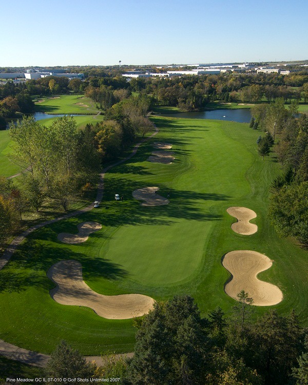 Aerial view of Hole 11 green and fairway lined by trees and 3 sand traps around the green